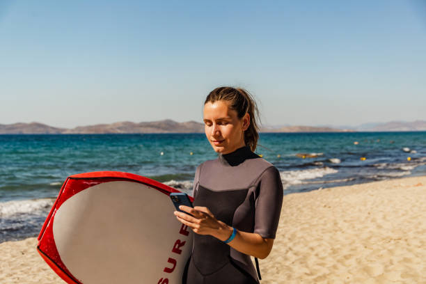 istock Young woman standing on the beach with her surfboard 1411663316