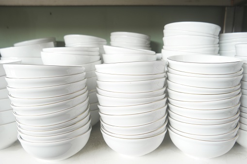 Stacks of white porcelain bowls imported from China are displayed on the rack. Sell cheaper than local made.