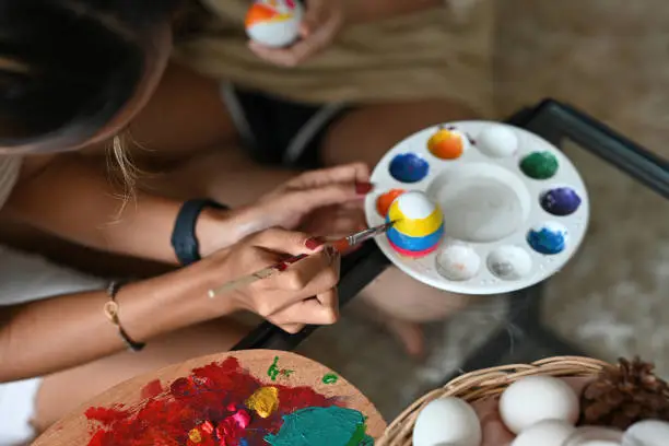 Top view of Easter egg on colorpalette was painted by Asian female preparing for Easter holiday party tonight.