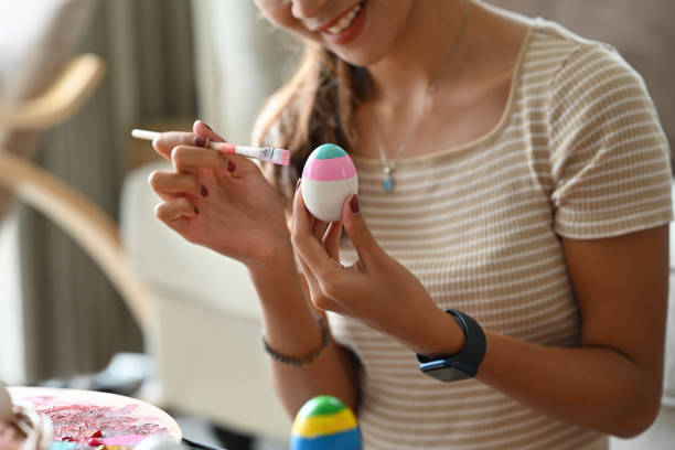 istock Close up Asian female hand holding Easter multi-colorful egg while work on art with acrylic watercolor and paintbrush. 1411664801