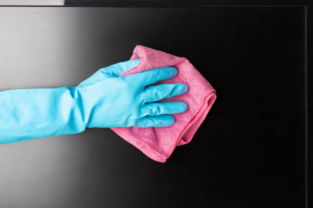 cleaning service, disinfection, hand in glove wipes dust from a computer monitor or TV screen with a rag stock photo
