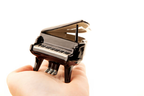 istock image of miniature piano hand white background 1411668687