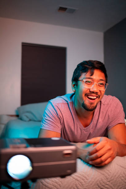 istock (Excited) Man Watching a Movie in Bed with Projector 1411669419