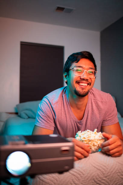 istock (Happy) Man Watching a Movie in Bed with Projector 1411669738