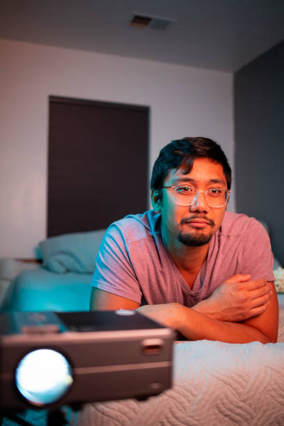 istock (Interested) Man Watching a Movie in Bed with Projector 1411669883