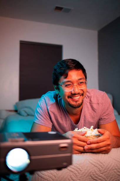 istock (Laughing) Man Watching a Movie in Bed with Projector 1411670752