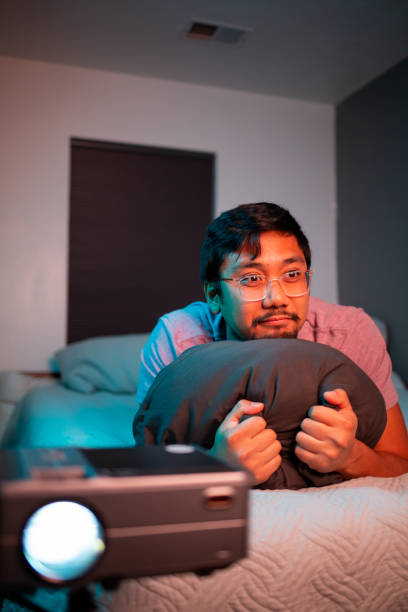 istock (Scared) Man Watching a Movie in Bed with Projector 1411671059