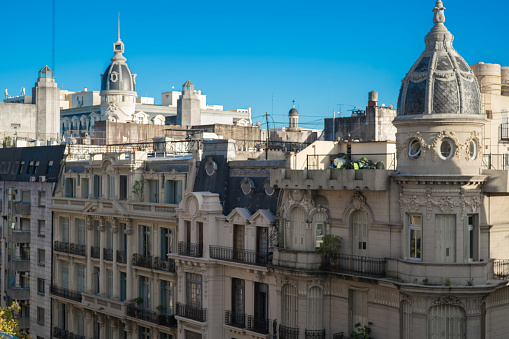 Front view from a terrace of the buildings with art novoux architecture located in Microcentro, Avenida de Mayo, Buenos Aires. With Parisian style and renowned domes.Illuminated by natural light, with a blue sky in the background.