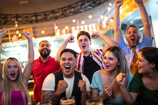 Friends watching and celebrating a sport match at a bar