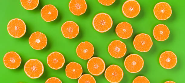 istock Fruit pattern of fresh orange slices on green background. Flat lay, top view. Pop art design, creative summer concept. Half of citrus in minimal style. 1411675453