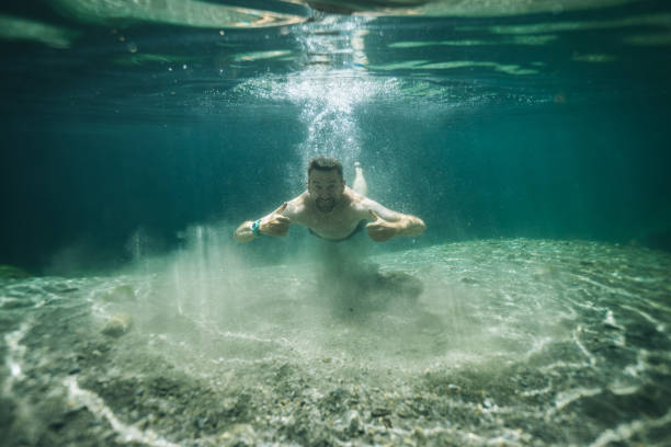istock Man swims in clear water pond 1411679292