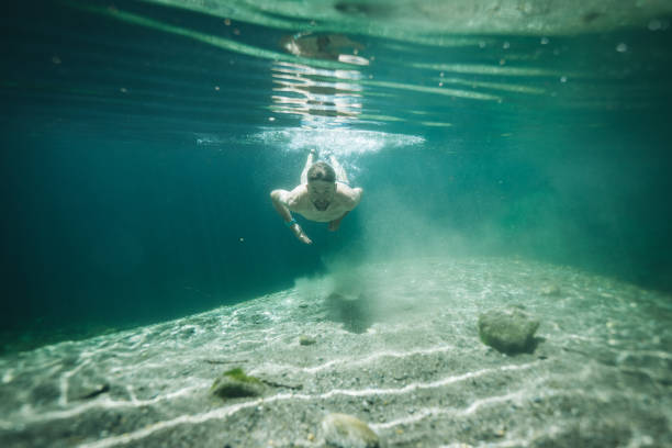 istock Man swims in clear water pond 1411679331