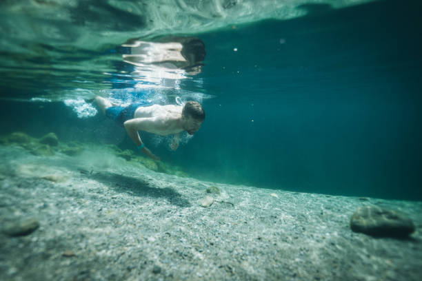 istock Man swims in clear water pond 1411679488