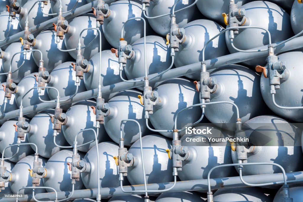 A lot of bottles filled with gas or gasoline are stacked in piles A lot of different small metal bottles filled with gas or gasoline are stacked in large piles and illuminated by the bright warm daytime sun Gas Stock Photo