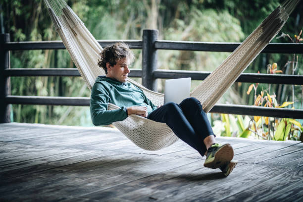 Young creative business man works from hammock outdoors stock photo