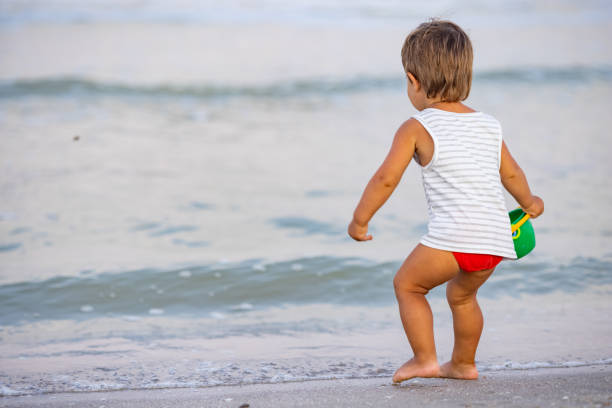 istock Kid collects shells and pebbles in the sea on a sandy bottom under the summer sun on a vacation 1411685529