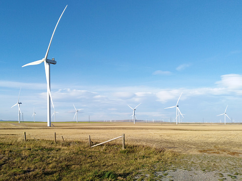 A Canadian prairie landscape with a wind turbine or wind farm near Pincher Creek, Alberta, Canada. The renewable energy, sustainability technology concept.