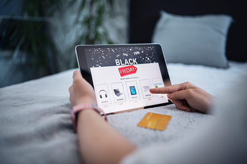 Unrecognizable woman using digital tablet to make online credit card purchase from online electronics store on sale.Black Friday sale.