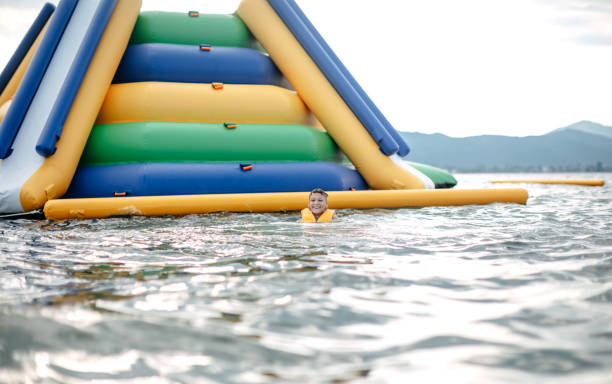 Kid having fun in Water Park Boy enjoying in Water Park trying to keep balance top of water slide photos stock pictures, royalty-free photos & images