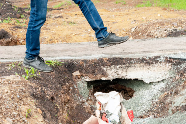 istock person's feet step over a hole near an asphalt sidewalk. 1411696611