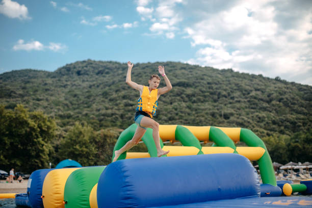 Kid having fun in Water Park Boy enjoying in Water park trying to keep balance top of water slide photos stock pictures, royalty-free photos & images