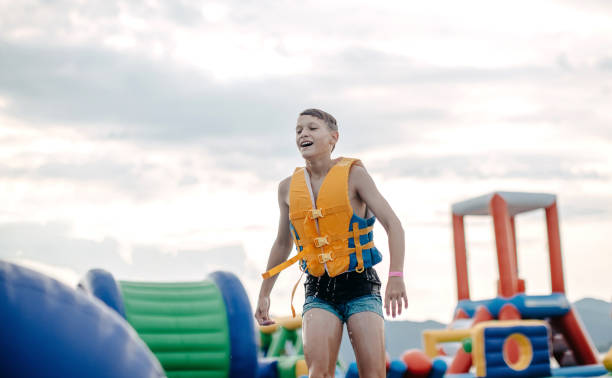 Kid having fun in Water Park Boy enjoying in Water Park trying to keep balance top of water slide photos stock pictures, royalty-free photos & images