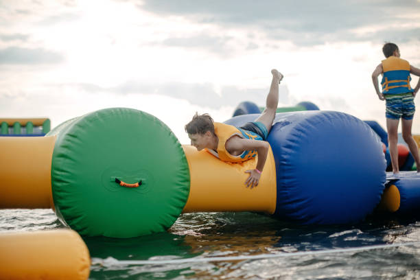 Kid having fun in Water Park Boy enjoying in Water Park trying to keep balance top of water slide photos stock pictures, royalty-free photos & images