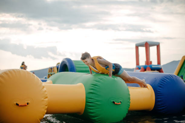Kid having fun in Water Park Boy enjoying in Water Park trying to keep balance top of water slide photos stock pictures, royalty-free photos & images