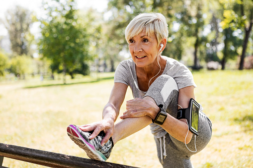 Old woman getting ready to run in the park by stretching