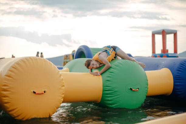 Kid having fun in Water Park Boy enjoying in Water Park trying to keep balance top of water slide photos stock pictures, royalty-free photos & images