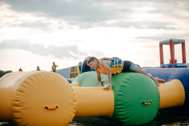 Kid having fun in Water Park Boy enjoying in Water Park trying to keep balance top of water slide photos stock pictures, royalty-free photos & images