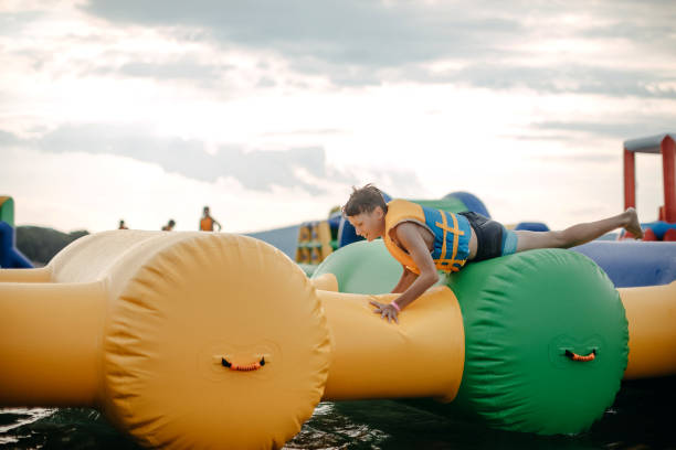 Kid having fun in Water Park Boy enjoying in Water Park trying to keep balance top of water slide photos stock pictures, royalty-free photos & images