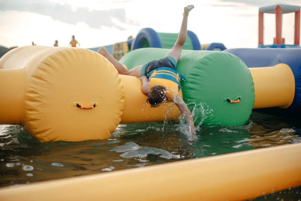 Kid having fun in Water Park Boy enjoying in Water Park trying to keep balance top of water slide photos stock pictures, royalty-free photos & images