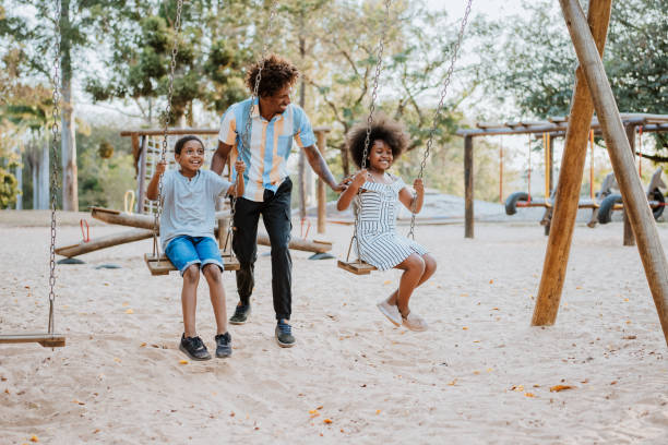 ojciec z córką i synem - child swinging playground african descent zdjęcia i obrazy z banku zdjęć