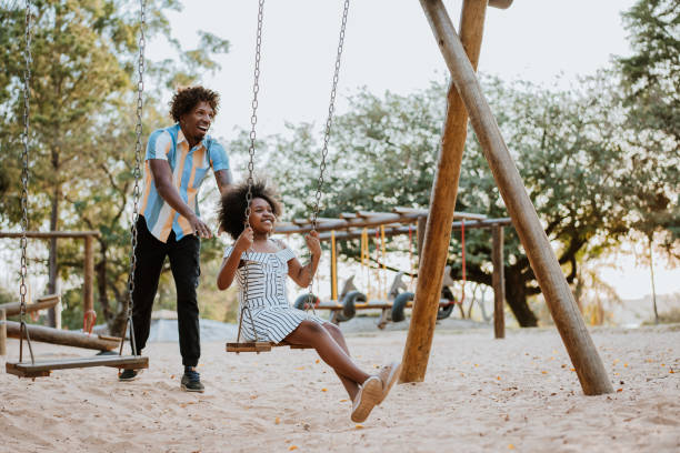 ojciec i córka na swing - child swinging playground african descent zdjęcia i obrazy z banku zdjęć