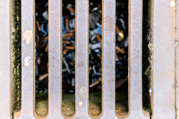 Cigarette butts in drain water sewer focus on grill stock photo