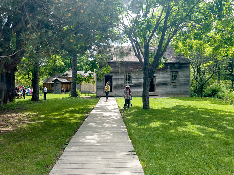 Tourists are walking on the road and enjoying the view. Black Creek Pioneer Village, previously Dalziel Pioneer Park, is an open-air heritage museum in Toronto, Ontario, Canada.