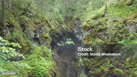 istock Top view hole in rock forest. Stock footage. In depths of forest there was collapse in mountain rock. Rock collapsed forming gloomy depression in forest landscape 1411700927