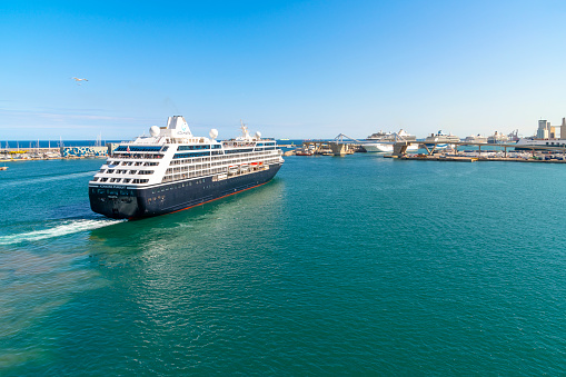 The Azamara Pursuit luxury cruise ship sails on the Mediterranean Sea as it leaves the port of Barcelona, Spain, on a sunny day.