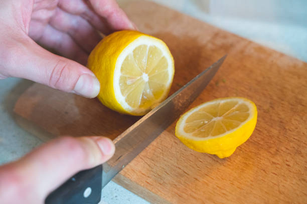 istock A woman cuts a lemon on a wooden kitchen board 1411702041