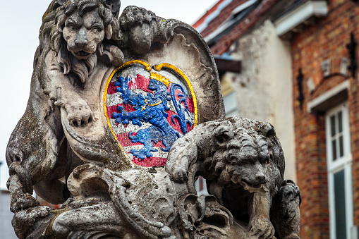 Lion and medieval stone empire golden shield in Bruges, Belgium