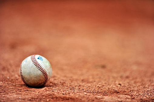 A baseball lies on the gravel outside the dugout prior to a minor league game.
