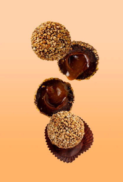 istock round candies sprinkled with nuts with fruit filling fly on an orange background, selective focus 1411708858