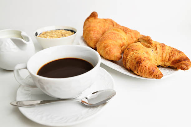 Coffee with croissant on a light background. Close-up. Free space for text. Breakfast theme. Beautiful morning breakfast with fresh croissants and granola.