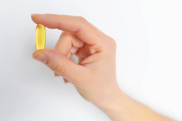 mano della donna che tiene la capsula di omega 3 isolata su sfondo bianco. primo piano. l'olio di pesce ad alta risoluzione è un integratore alimentare derivato dal fegato di merluzzo, ha acidi grassi omega-3, epa, dha - gel capsules foto e immagini stock