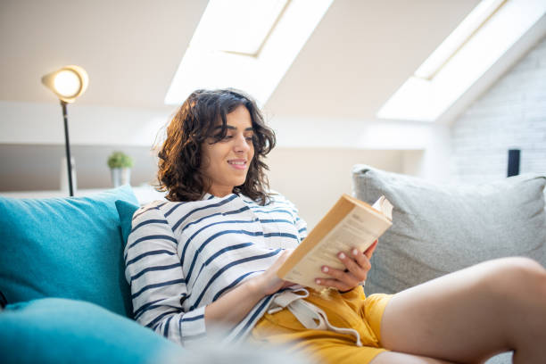 istock Happy woman reading book at home 1411710330