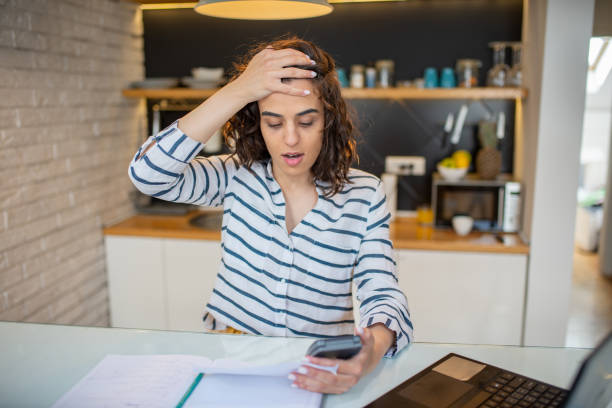 istock Young woman using calculator while going through bills and home finances 1411710966