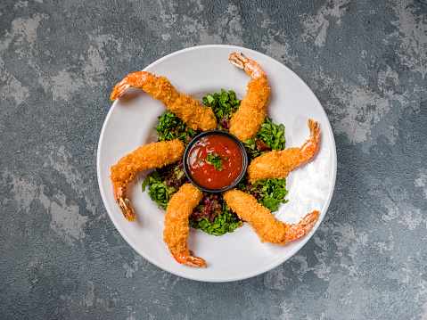 shrimp tempura with hot sauce on white plate on gray background