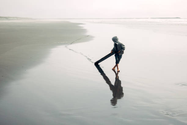 A Caucasian boy plays in the waves and sand on a Pacific Ocean beach in Washington state.  The beauty of the Pacific Northwest.