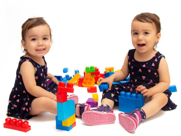 istock Two year old twin girls playing blocks 1411714796